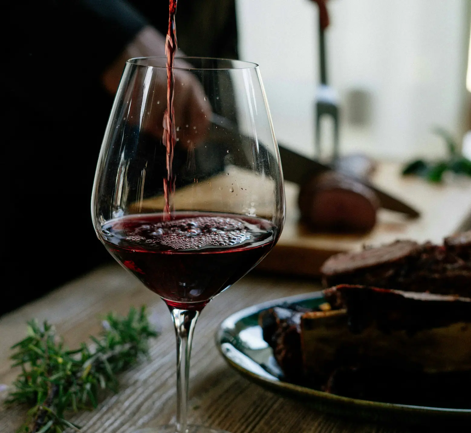 Verre de vin rouge servi à table avec viande grillée en arrière-plan