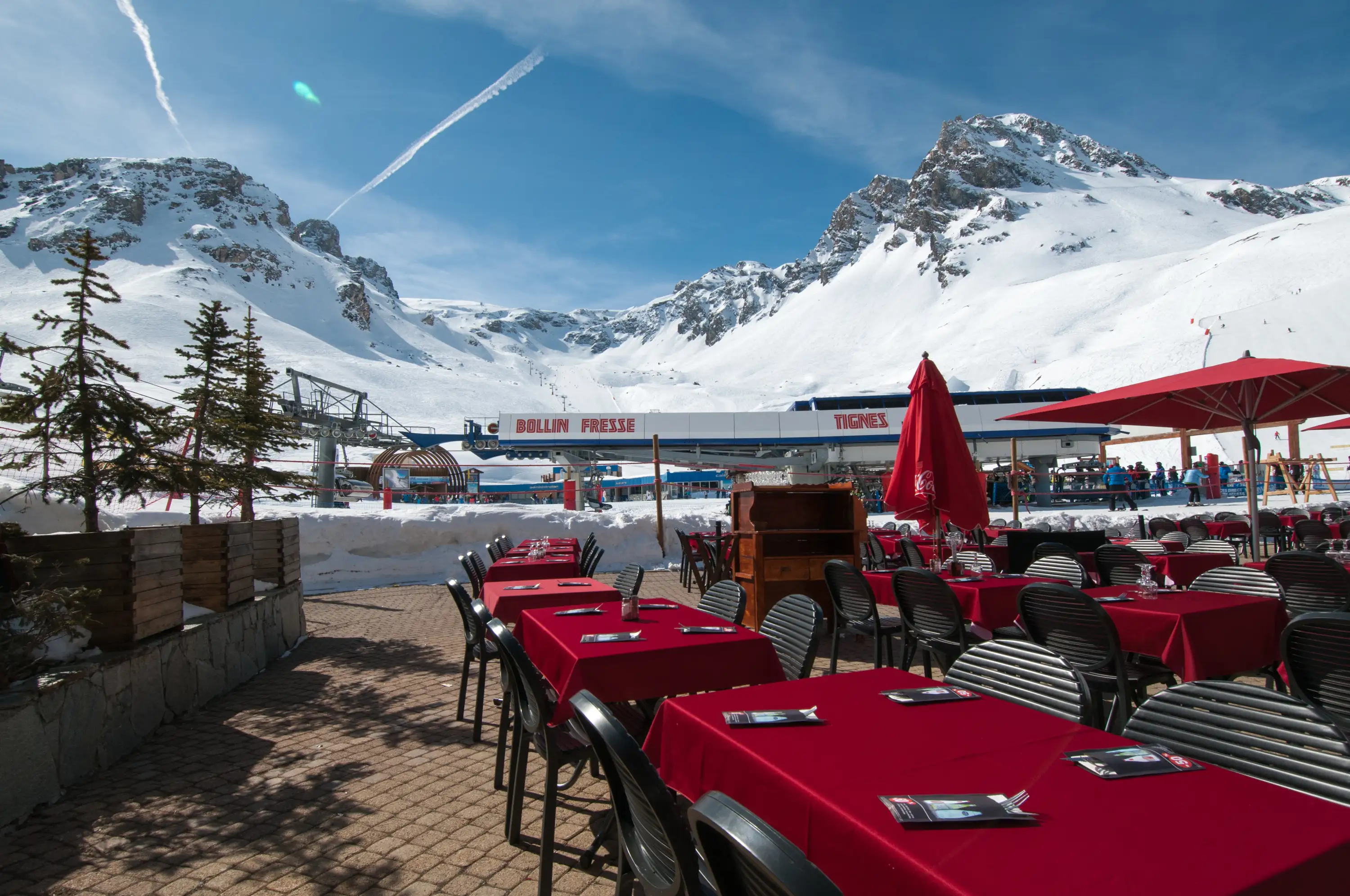 Terrasse du restaurant avec tables nappées de rouge et vue sur les pistes de Tignes